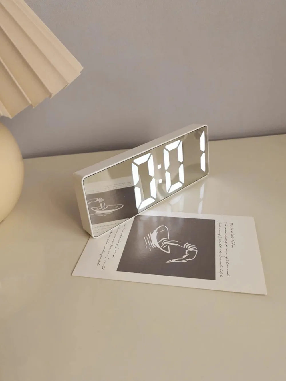 Reloj despertador moderno minimalista con control por voz, multifuncional y portátil con pantalla LED y superficie de espejo en blanco y negro.