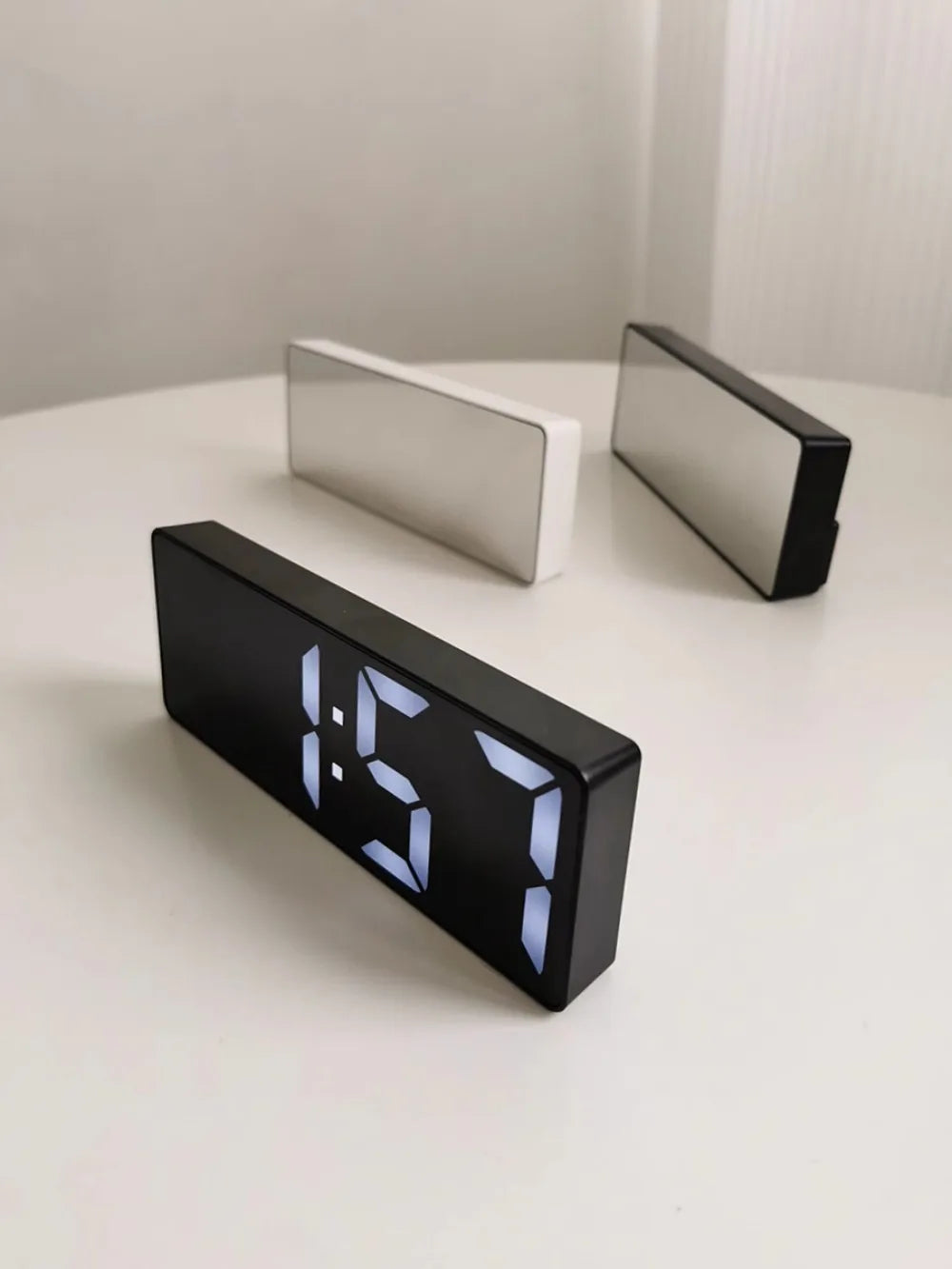 Reloj despertador moderno minimalista con control por voz, multifuncional y portátil con pantalla LED y superficie de espejo en blanco y negro.