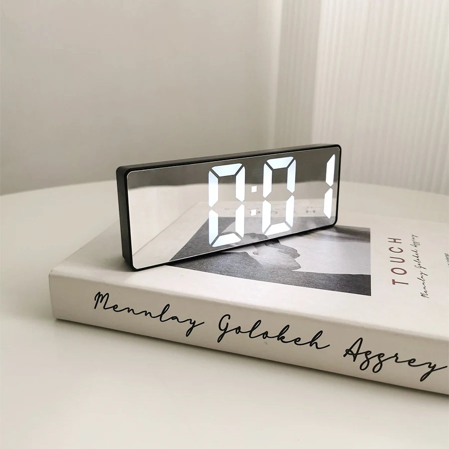 Reloj despertador moderno minimalista con control por voz, multifuncional y portátil con pantalla LED y superficie de espejo en blanco y negro.
