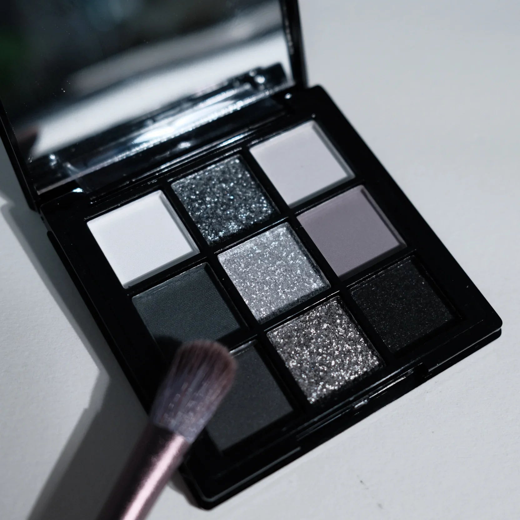 Paleta de sombras de ojos de 9 tonos: Black Swan, Smoky, Dark Black, Grey Silver Glitter, acabado mate, larga duración y fácil de aplicar.